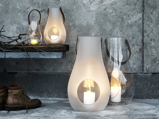 Et fremragende eksempel på stilfulde og smukke gaver til kvinder: Design med lys-lanterne fra Holmegaard lavet af gennemsigtigt eller matt hvidt glas og et læderhåndtag.